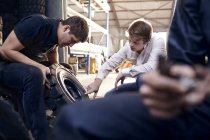 Mecânico e cliente examinando pneu na oficina de reparação de automóveis — Fotografia de Stock