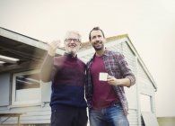 Padre e hijo hablando y bebiendo café fuera de casa - foto de stock