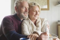 Lächelndes Senioren-Paar umarmt und weggeschaut — Stockfoto