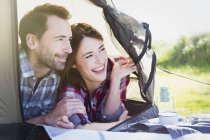 Smiling couple peering from inside tent — Stock Photo