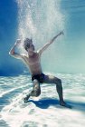 Homme posant sous l'eau dans la piscine — Photo de stock