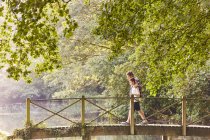 Padre e hijo cruzando pasarela en parque con árboles - foto de stock