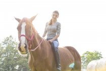 Lächelnde Frau reitet Pferd bareback — Stockfoto