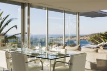 Set table in modern dining room overlooking ocean — Stock Photo