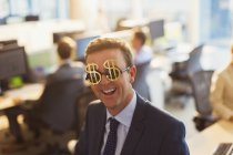 Portrait smiling businessman wearing dollar sign sunglasses in office — Stock Photo