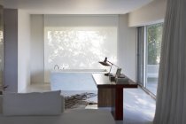Desk and bathtub in modern house — Stock Photo