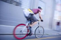 Bicycle messenger speeding down urban street — Stock Photo