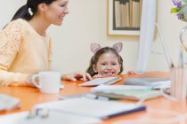 Portrait smiling girl in mouse ears headband with mother at computer — Stock Photo