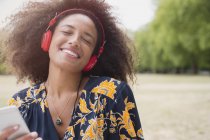 Mulher entusiasmada ouvindo música com fones de ouvido e mp3 player no parque — Fotografia de Stock