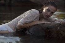Portrait of sensual woman laying on rock in river — Stock Photo