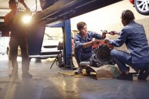 Mecânica discutindo parte na oficina de reparação de automóveis — Fotografia de Stock