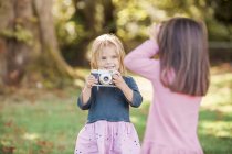 Toddler girls playing with camera in park — Stock Photo