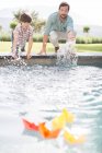 Pai e filho correndo barcos de papel na piscina — Fotografia de Stock