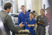 Mechanics discussing car engine in auto repair shop — Stock Photo