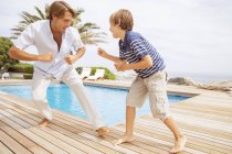 Батько і син грають біля басейну — стокове фото