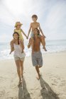 Parents carrying children on shoulders at beach — Stock Photo