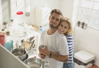 Portrait smiling young couple hugging in apartment kitchen — Stock Photo