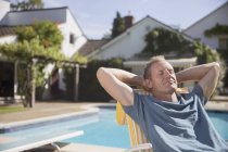 Hombre caucásico feliz relajándose junto a la piscina - foto de stock