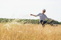 Juguetona mujer mayor bailando en el soleado campo rural - foto de stock