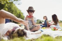 Sorridente ragazzo mangiare anguria su coperta in campo soleggiato — Foto stock