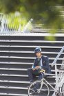 Homme d'affaires avec casque et textos de vélo avec téléphone portable sur les escaliers urbains — Photo de stock
