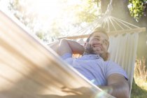 Усміхнений молодий чоловік розслабляється в літньому гамаку — стокове фото