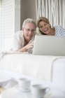 Älteres Paar benutzt Laptop auf dem Bett — Stockfoto