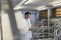 Winzer im Laborkittel mit Klemmbrett im Weinkeller — Stockfoto