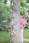 Бабушка и внуки, заглядывающие за дерево — стоковое фото