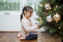 Kleinkind schmückt Weihnachtsbaum — Stockfoto