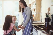 Madre e figlie che si tengono per mano in cucina — Foto stock