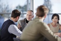Успешные взрослые бизнесмены разговаривают на встрече — стоковое фото