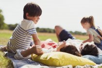 Family relaxing on blanket in sunny field — Stock Photo