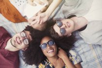 Overhead portrait smiling friends laying in circle on blanket — Stock Photo