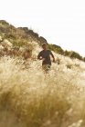 Mann läuft durch hohes, sonniges Gras — Stockfoto