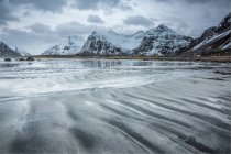 Montagne innevate dietro la spiaggia fredda, Skagsanden Beach, Isole Lofoten, Norvegia — Foto stock