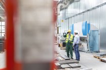 Инженер и рабочий разговаривают на заводе — стоковое фото