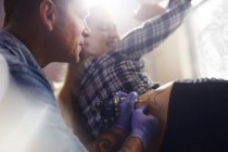 Tatuagem artista tatuando mulher quadril no estúdio — Fotografia de Stock
