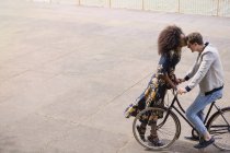 Ласковая женщина целует мужчину на велосипеде — стоковое фото