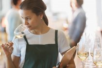 Сотрудник винодельни нюхает белое вино в дегустационной — стоковое фото