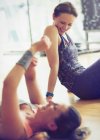Lächelnde Frauen ruhen sich auf dem Boden des Fitnessstudios aus — Stockfoto