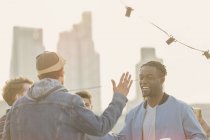 Young men high fiving at rooftop party — Stock Photo