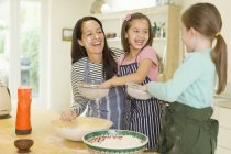 Mãe rindo e filhas assando com farinha em rostos na cozinha — Fotografia de Stock