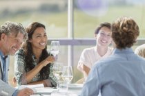 Amigos bebiendo vino y hablando en la mesa del restaurante - foto de stock