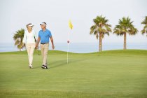 Senior couple walking on golf course — Stock Photo