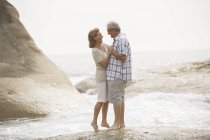 Coppia anziana che si abbraccia sulla spiaggia — Foto stock