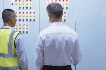 Supervisor and worker at control panel in factory — Stock Photo