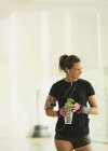 Lächelnde Frau macht Pause und trinkt Wasser im Fitnessstudio — Stockfoto