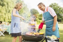 Famiglia multi-generazione in piedi al barbecue in cortile — Foto stock