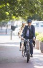 Бизнесмен в костюме и шлеме катается на велосипеде по дорожке — стоковое фото